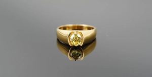 Détail d'une bague de luxe en or avec un grand cristal jaune et un reflet poli élégant