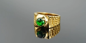 Detailed close-up of men's gold titanium steel ring with a green center gemstone