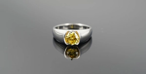 Gros plan d'une bague en acier titane avec une grande pierre précieuse jaune et reflet
