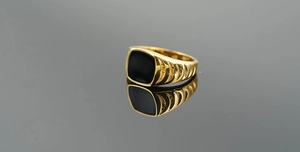 Macro detail of men's vintage gold ring with black square stone and embossed sides