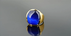 Macro di un anello da uomo vintage dorato con una pietra quadrata blu occhio di gatto