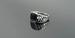 Macro detail of men's stainless steel signet ring with black square inlay and side grooves