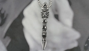 Macro shot of silver Vajra pestle pendant with retro oxidation and deity carvings