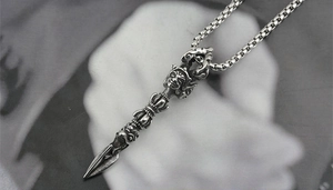 Macro view of vintage silver vajra pendant with intricate deity carvings and box chain