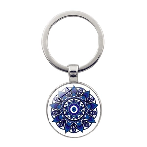 Macro shot of the blue Evil Eye charm and intricate mandala patterns on a silver keychain