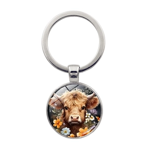 Silver keychain with glass pendant featuring a Highland cow and orange flowers on white background