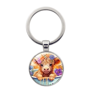 Detail of metal keychain featuring a Highland cow with floral crown under glass dome