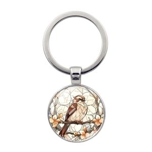 Vue détaillée du porte-clés en métal argenté avec pendentif colibri et motifs floraux