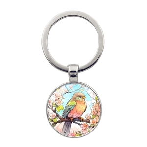 Détail de l'illustration de colibri sur un porte-clés rond en alliage et dôme de verre
