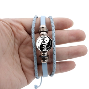 Detail of light blue multilayer braided leather bracelet with yin yang dragon charm