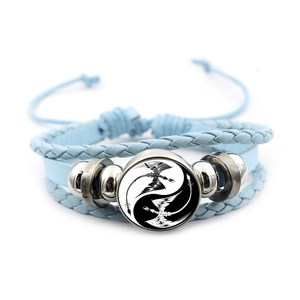 Detail of light blue leather braided bracelet with Yin Yang dragon glass cabochon