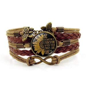 Detail of bohemian layered bracelet featuring sunflower quote and butterfly charms
