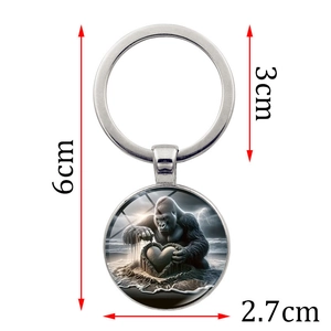 Silver metal keychain with a round glass pendant featuring a gorilla and heart beach scene