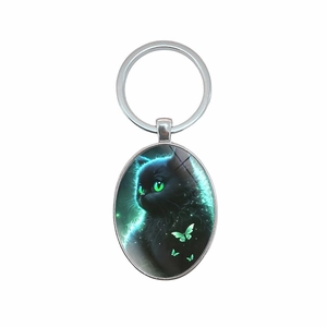 Oval keychain with green-eyed black cat and magic forest scene in silver finish