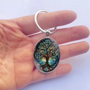 Porte-clés Arbre de Vie argenté avec pendentif ovale coloré tenu à la main
