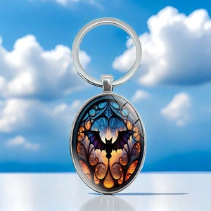 Macro detail of gothic bat stained glass pattern under oval glass dome on silver keyring