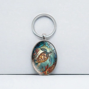 Oval silver metal keychain featuring a sea turtle mosaic art pendant with ocean background