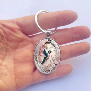 Fashionable oval hummingbird pendant keychain with 3D floral design in silver metal