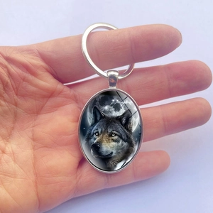 Portachiavi ovale in argento con ciondolo lupo e luna e anello in metallo tenuto in mano