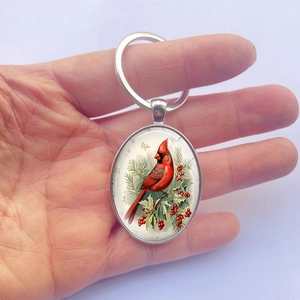 Vintage oval silver keychain featuring a red cardinal bird on a berry branch