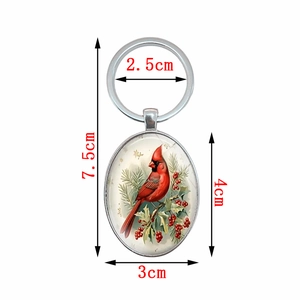 Vintage oval Northern Cardinal bird keychain with silver metal frame and winter holly pattern