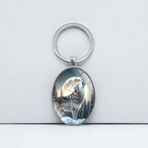 Porte-clés ovale avec loup hurlant sous la lune et anneau en métal poli brillant
