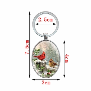 Oval Cardinal bird keychain with winter snow illustration and dimensions display