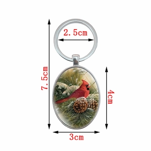 Northern cardinal red bird oval metal keychain with pine branch design and silver keyring