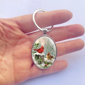 Oval keychain with red cardinal birds and winter snow scenery on a metal ring