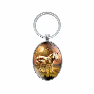 Oval silver metal keychain with artistic painting of horses under the moon on white background