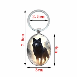 Oval keychain featuring wild black wolf design in snowy mountains with metal ring