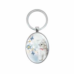 Porte-clés ovale en métal argenté avec chat blanc, fleurs bleues et motif papillon