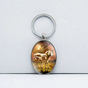 Oval silver metal keychain with a horse and foal sunset illustration on a brushed background