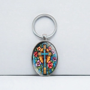 Oval silver keychain featuring a stained glass cross and colorful floral art pattern