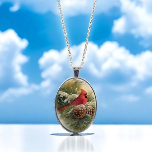 Detail of cardinal bird oval pendant necklace with pine branches and silver chain