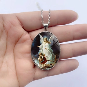 Vintage oval angel pendant necklace with a silver chain shown in a hand-held display