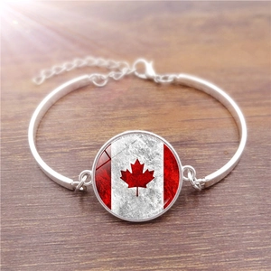 Detailed close-up of Canada flag glass gem pendant on a silver-toned adjustable bracelet