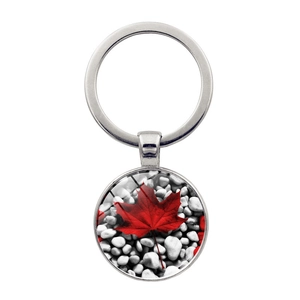 Detalle de llavero plateado con colgante de cúpula de vidrio de hoja de arce roja en blanco