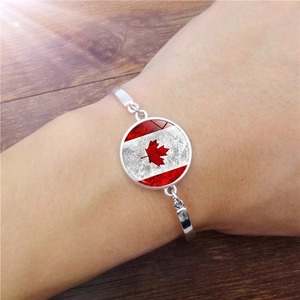 Detail view of a silver bracelet featuring a Canada flag maple leaf glass pendant