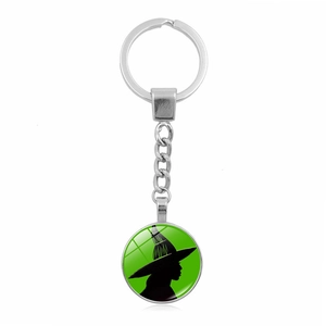 Gros plan d'un porte-clés argenté avec pendentif vert illustrant une sorcière noire