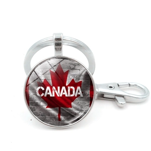 Detailed macro view of Canada flag metal keychain with red maple leaf and lobster clasp
