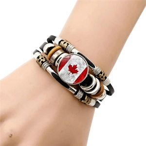 Detailed close-up of multilayer leather bracelet featuring a Canada flag maple leaf charm