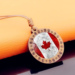 Detail of wooden necklace featuring carved swirls and a vintage Canadian flag pendant