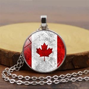 Detail of round Canada flag maple leaf pendant on silver chain over wooden background