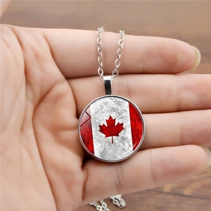 Close-up of silver necklace featuring a vintage round Canadian flag maple leaf pendant