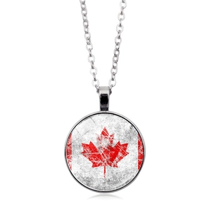 Macro shot of silver round pendant necklace with vintage Canadian flag maple leaf pattern