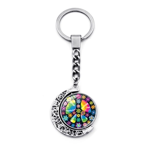 Macro detail of rotating moon pendant keychain with peace sign and floral pop art pattern