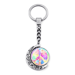 Detail of a rotating peace sign moon pendant keychain made of silver-colored alloy