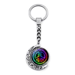 Detailed close-up of rotating crescent moon keychain with rainbow peace sign glass pendant