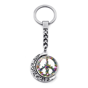 Close-up of crescent moon pendant with colorful butterfly peace sign on silver keychain